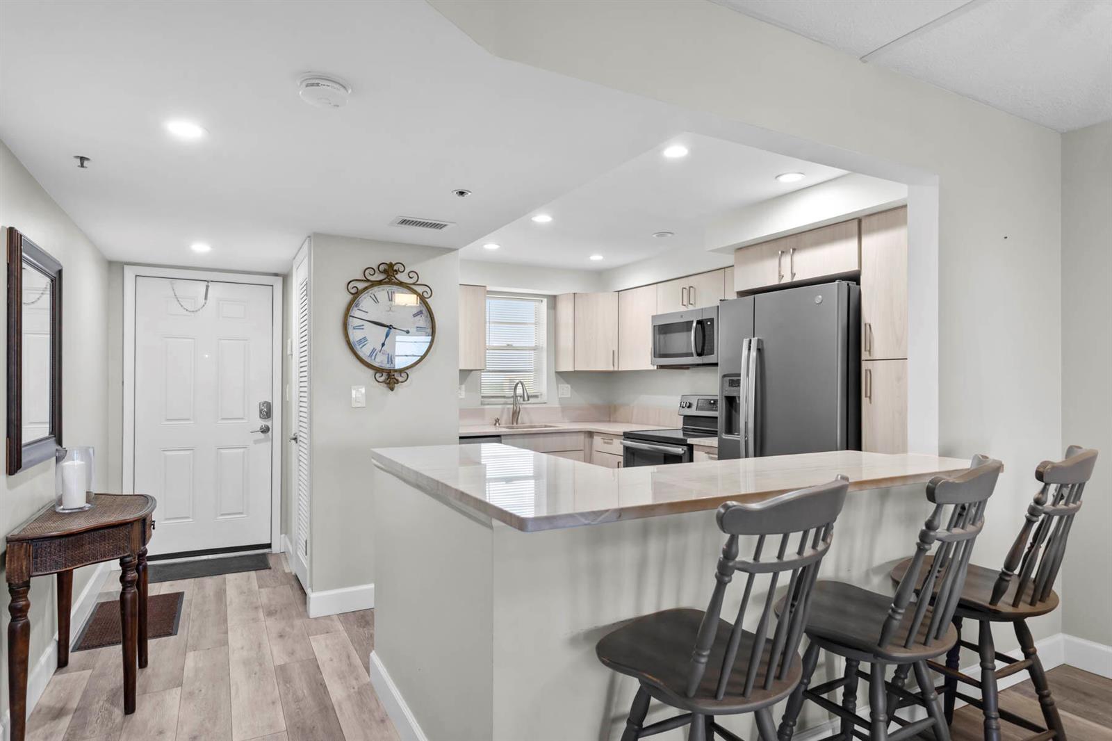 A kitchen with light wood cabinets, stainless steel appliances, and a breakfast bar with stools — 3150 W Rolling Hills Circle # 704, Davie FL 33328, DAVIE, FL