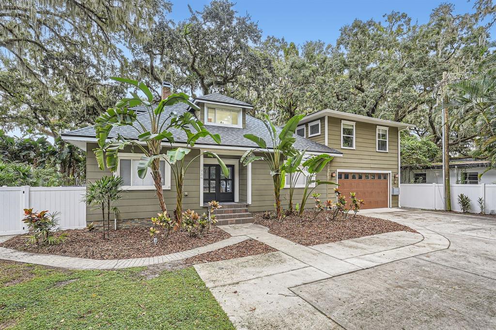 A two-story house with olive green siding, a brown garage door, and large tropical plants — 734 S MILLS AVENUE, ORLANDO, FL
