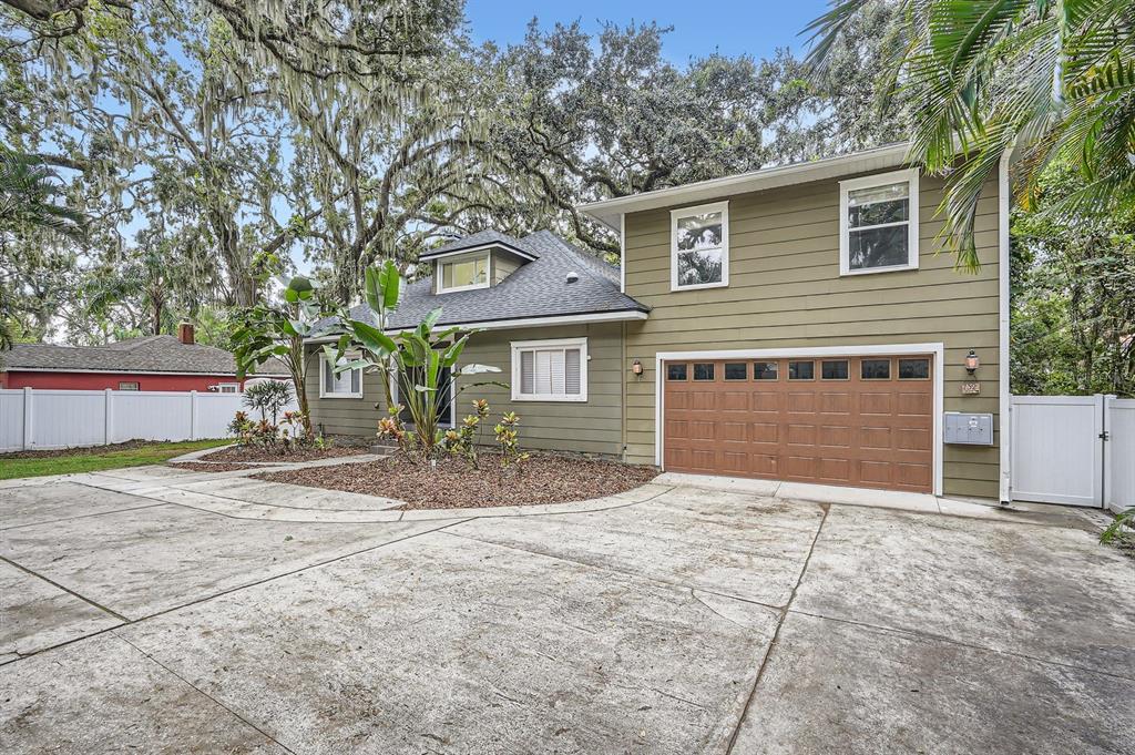 A two-story house with olive green siding, a brown garage door, and a concrete driveway — 734 S MILLS AVENUE, ORLANDO, FL