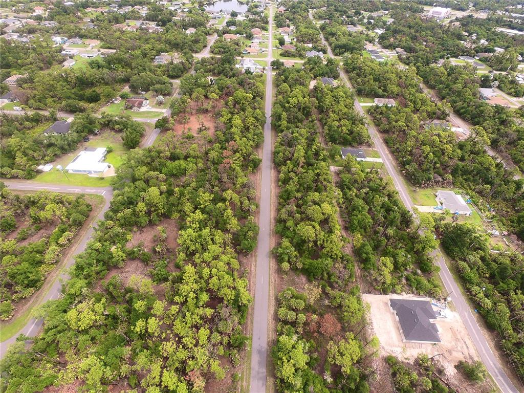 An aerial view shows a paved road running through a wooded residential area with houses — 1101, 1117 & 1109 BORDER STREET, PORT CHARLOTTE, FL