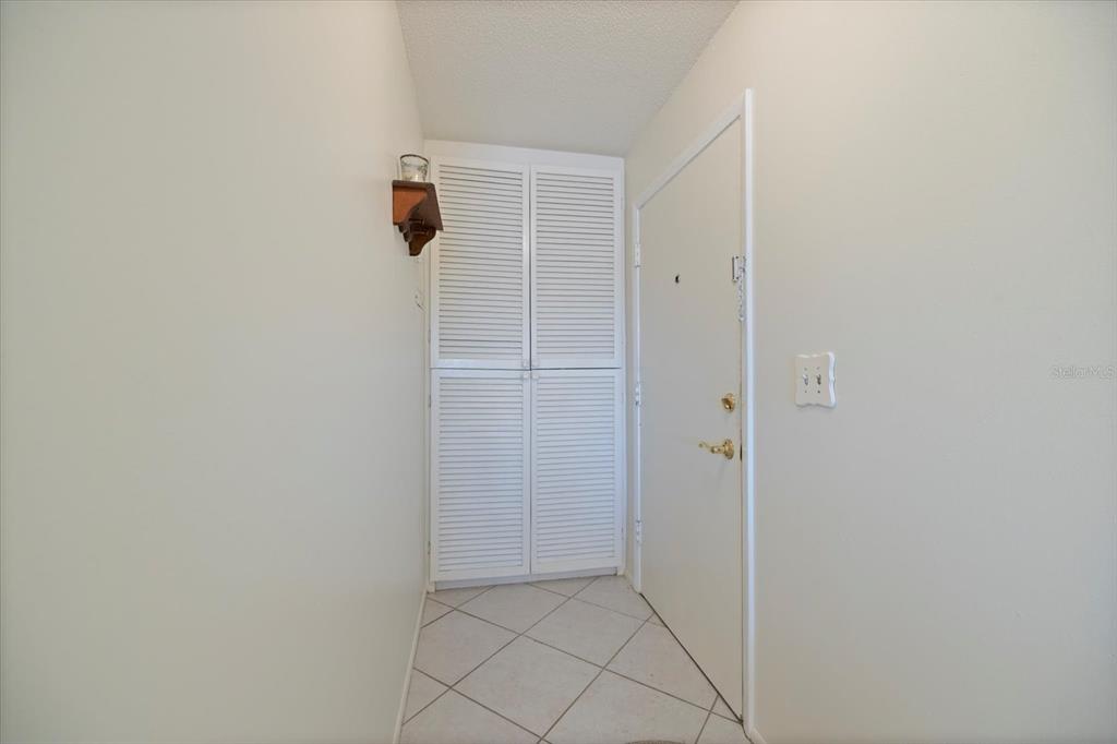 A small entryway features white louvered closet doors, tiled flooring, and a white front door — 649 TAMIAMI TRAIL S UNIT 301, VENICE, FL
