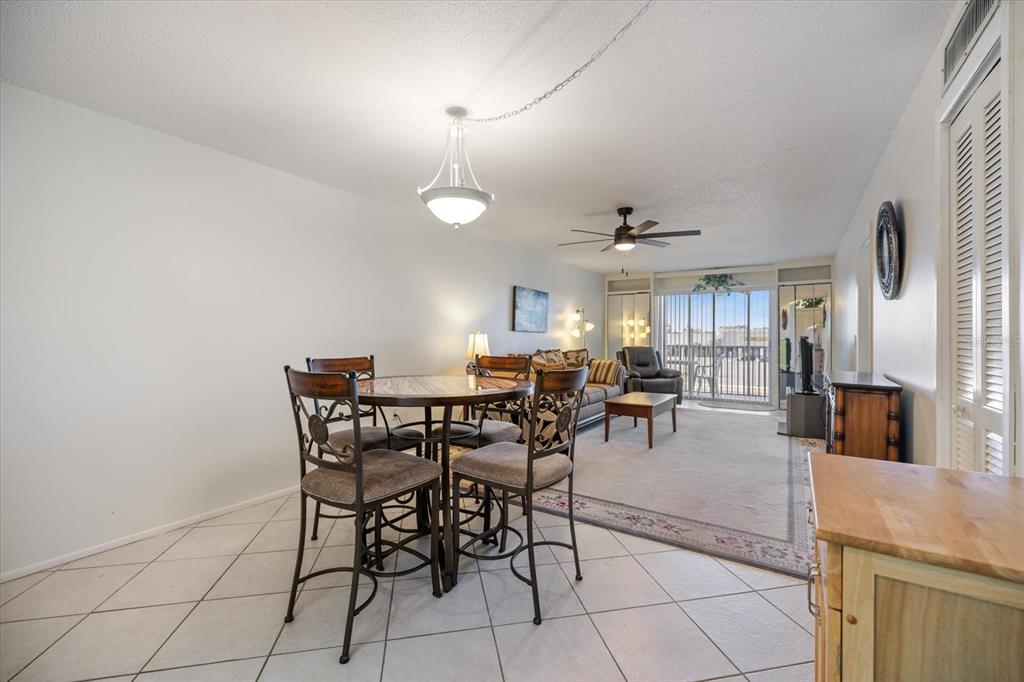 A dining area with a round table and chairs opens into a carpeted living room — 649 TAMIAMI TRAIL S UNIT 301, VENICE, FL