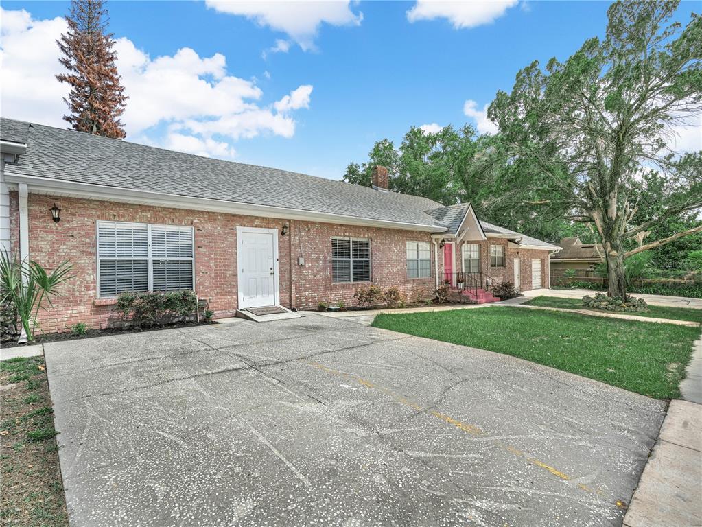 A single-story brick house features a concrete driveway, a white front door, and a lawn — 221 CITRUS GROVE BOULEVARD S, POLK CITY, FL