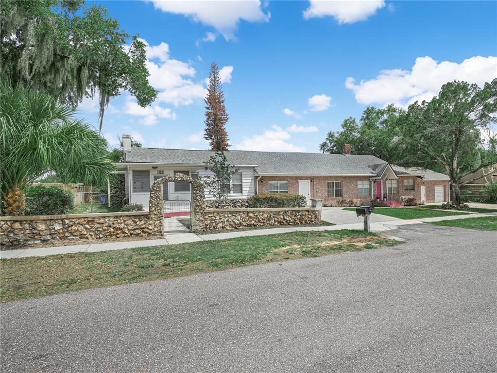 A single-story house with a stone wall, arched gate, and a mix of brick and siding — 221 CITRUS GROVE BOULEVARD S, POLK CITY, FL