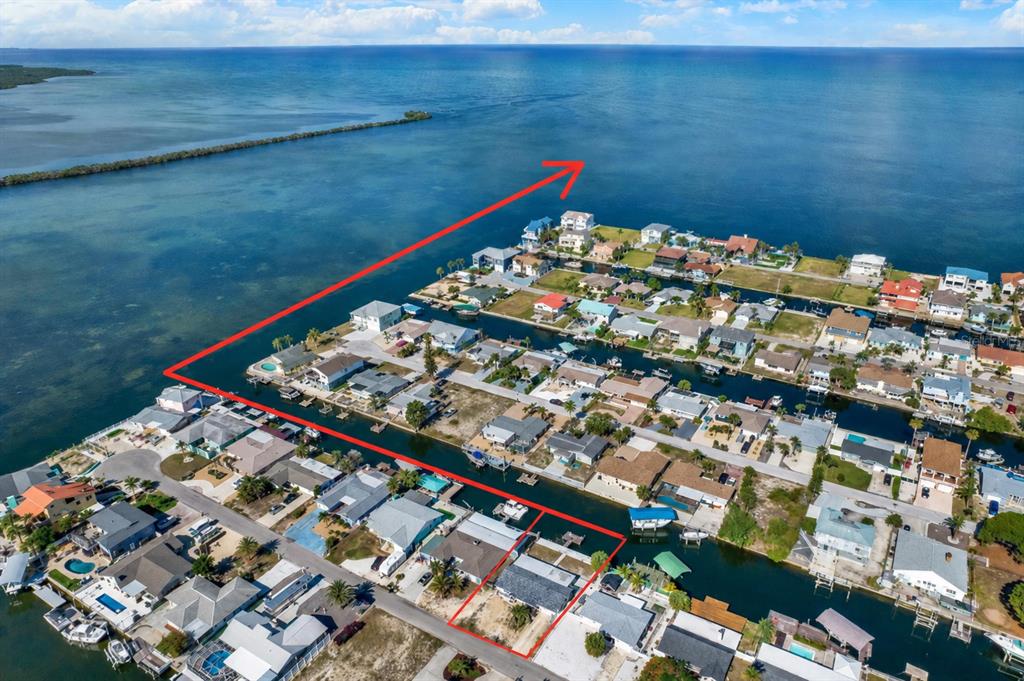 An aerial view shows a waterfront house with a red outline, canals, and the open ocean — 13605 GARRIS DRIVE, HUDSON, FL