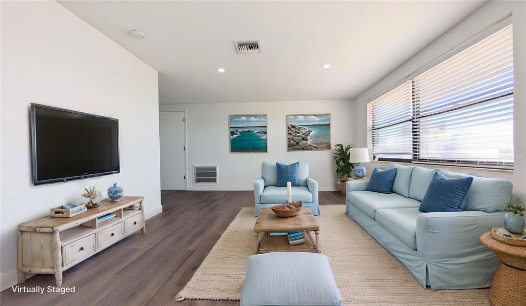 A living room features light blue furniture, a wooden media console, and wood-look flooring — 13605 GARRIS DRIVE, HUDSON, FL