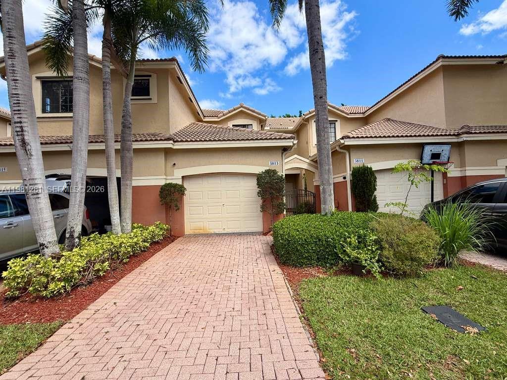 A two-story townhouse exterior features a brick paver driveway, two garage doors, and palm trees — 3813 Tree Top Dr, Weston FL 33332, WESTON, FL