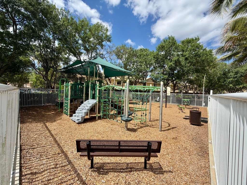 A fenced playground features a climbing structure, a shade canopy, and a park bench — 3813 Tree Top Dr, Weston FL 33332, WESTON, FL