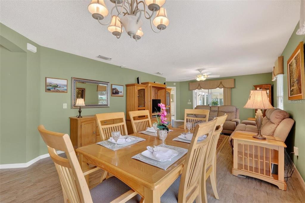 A dining area with a wooden table and chairs flows into a living room space — 1258 ESTILL AVENUE, THE VILLAGES, FL
