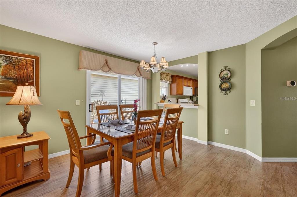 A dining room with wood floors, a wooden table, and a view into the kitchen — 1258 ESTILL AVENUE, THE VILLAGES, FL
