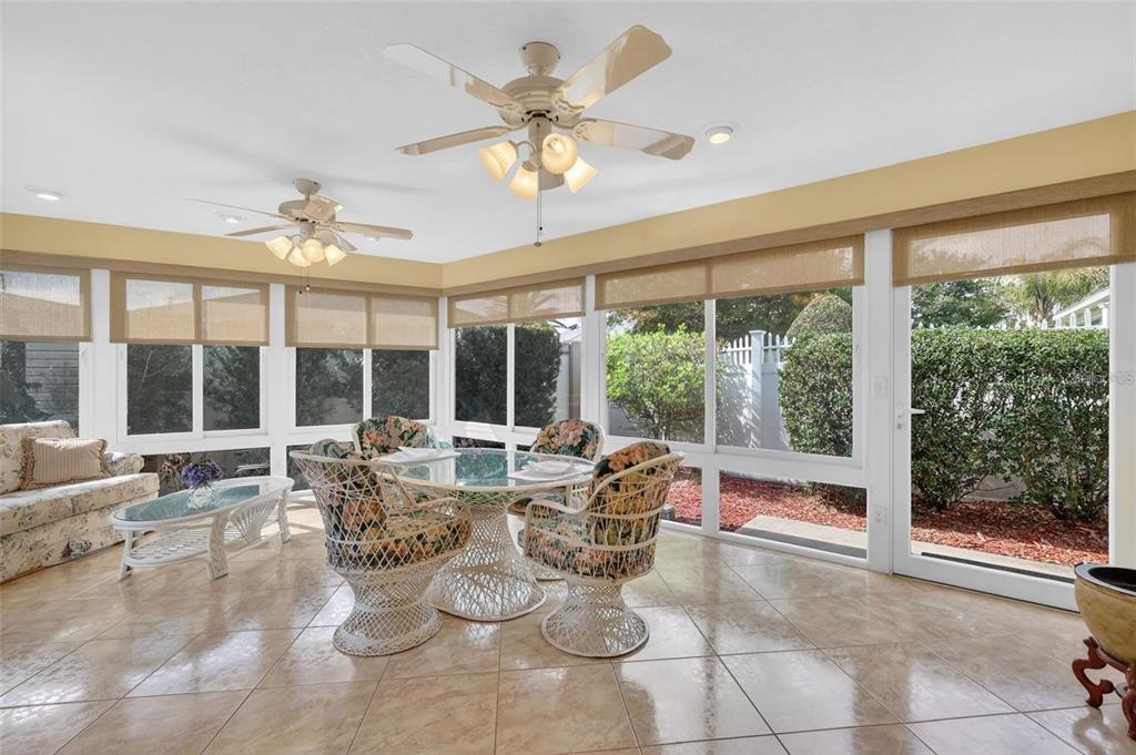 A sunroom features tile flooring, two ceiling fans, a dining set, and large glass windows — 1258 ESTILL AVENUE, THE VILLAGES, FL