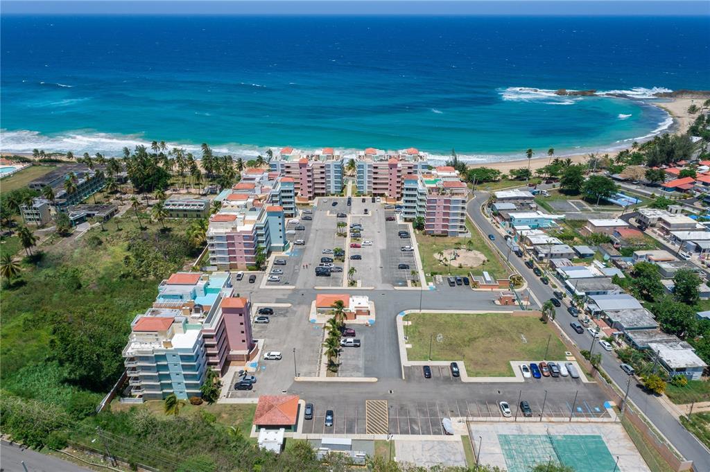 An aerial view shows a multi-building apartment complex with parking lots located near a beach — 1 ISABELA BEACH COURT UNIT 752, ISABELA, PR