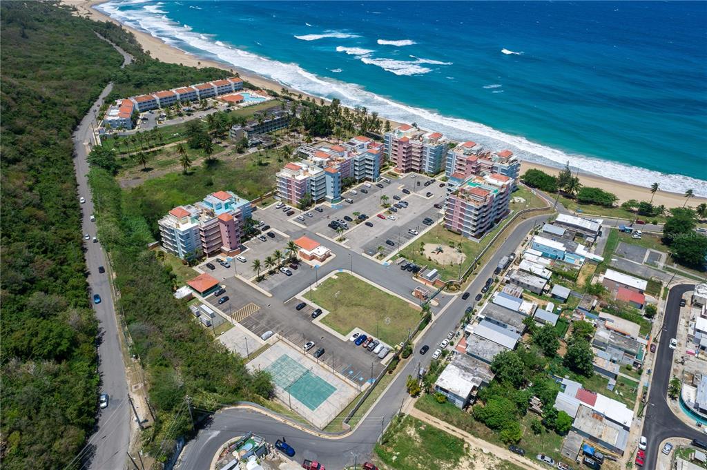 An aerial view shows a coastal apartment complex with parking lots and a tennis court — 1 ISABELA BEACH COURT UNIT 752, ISABELA, PR