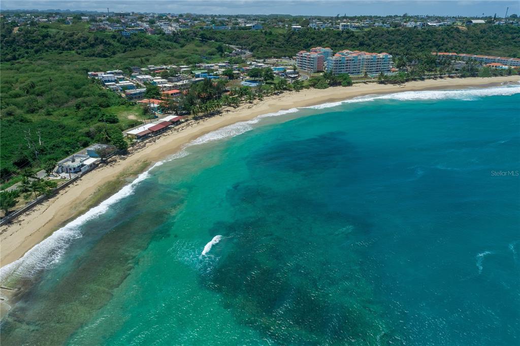 An aerial view of a sandy beach coastline with turquoise water and nearby residential buildings — 1 ISABELA BEACH COURT UNIT 752, ISABELA, PR