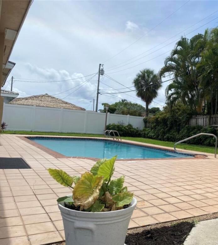 A backyard features a rectangular swimming pool, a tiled patio, and a white privacy fence — 1230 SE 14th Drive, Deerfield Beach FL 33441, DEERFIELD BEACH, FL