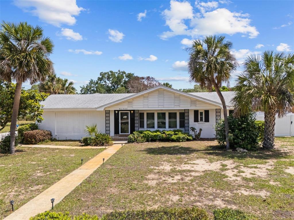 A single-story white house with a gabled roof and palm trees in the front yard — 1117 N LAKESHORE BOULEVARD, LAKE WALES, FL