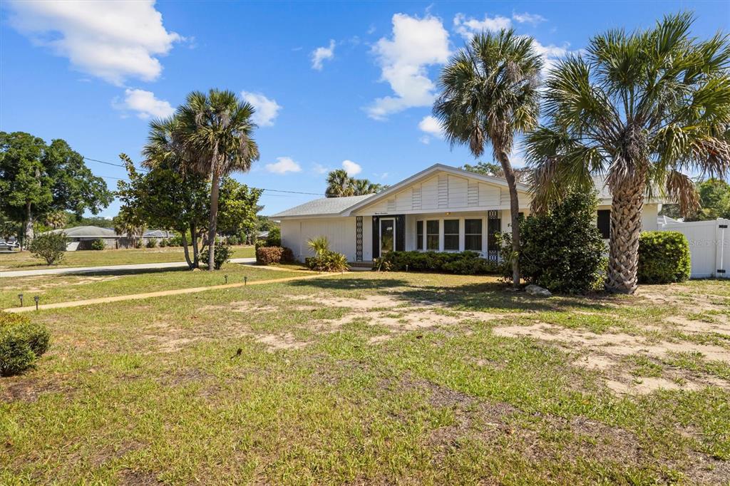 A single-story house with a white exterior and palm trees sits on a grassy lot — 1117 N LAKESHORE BOULEVARD, LAKE WALES, FL
