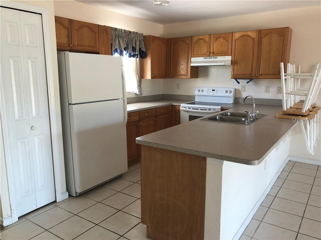 A kitchen features wood cabinets, a white refrigerator, a stove, and a laminate countertop — 27082 ADAMS STREET UNIT B, PUNTA GORDA, FL