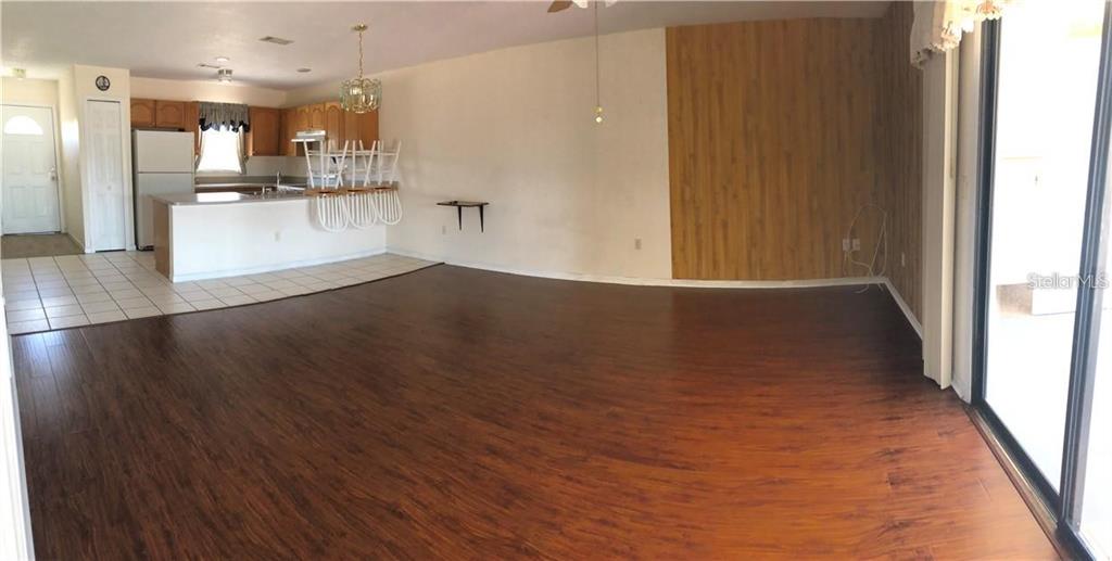 An open-concept living and dining area features dark wood flooring and a kitchen with white cabinets — 27082 ADAMS STREET UNIT B, PUNTA GORDA, FL