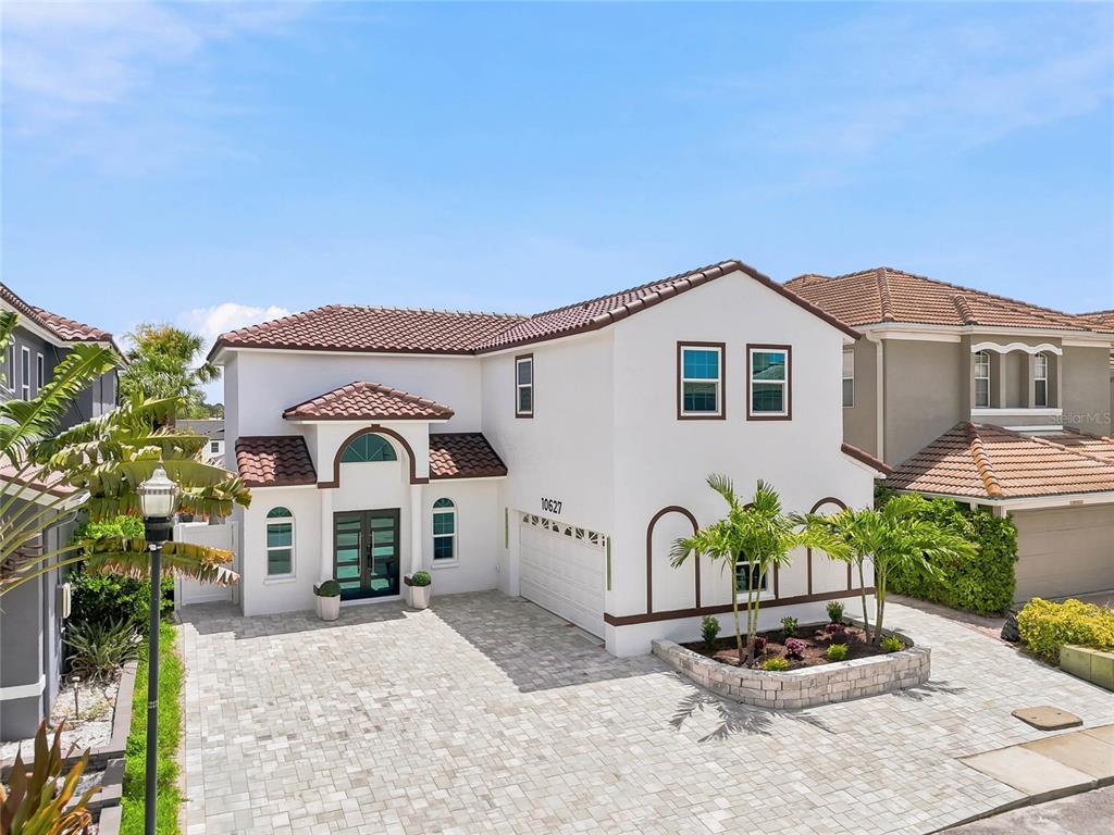 A two-story stucco house with a tiled roof, arched entryway, and a paved driveway — 10627 HATTERAS DRIVE SW, TAMPA, FL