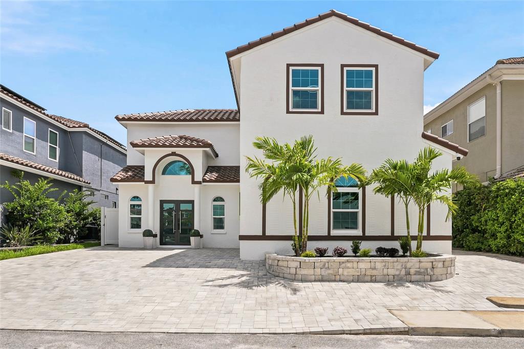 A two-story white stucco house features a tiled roof, arched windows, and a paved driveway — 10627 HATTERAS DRIVE SW, TAMPA, FL