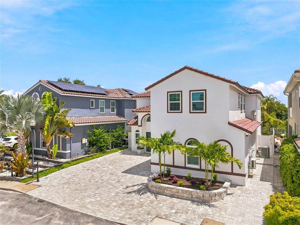 A white two-story house with a paved driveway and a small front garden area — 10627 HATTERAS DRIVE SW, TAMPA, FL