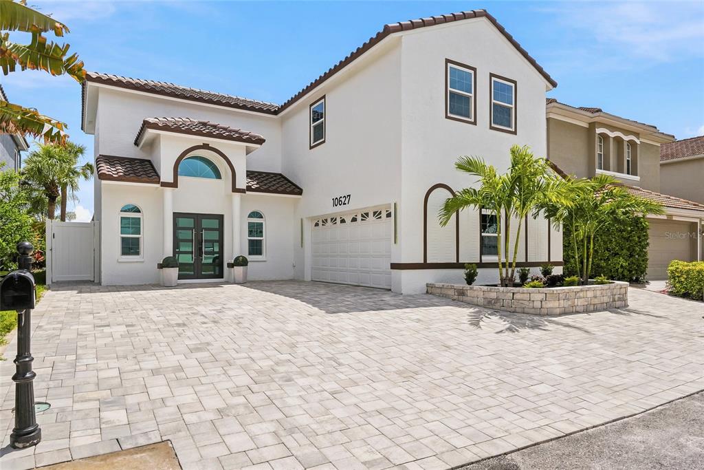 A two-story white stucco house features a tiled roof, arched entryway, and paved driveway — 10627 HATTERAS DRIVE SW, TAMPA, FL