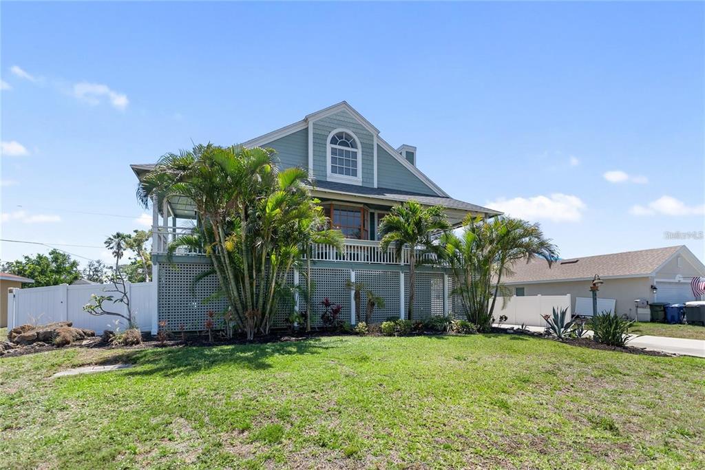 A two-story house with a raised foundation, lattice skirting, and a wraparound porch — 861 NECTAR ROAD, VENICE, FL