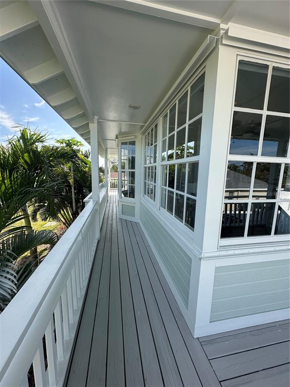 A covered wooden balcony with white railings overlooks palm trees and a residential area — 861 NECTAR ROAD, VENICE, FL