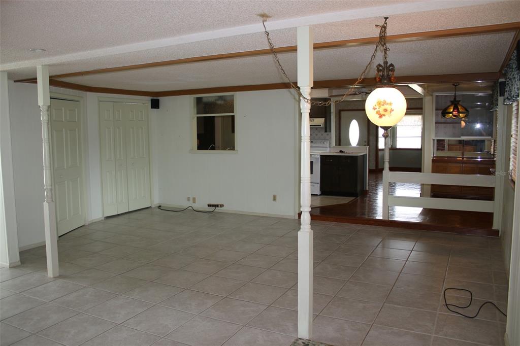 A living room with tile flooring, white support columns, and a view into the kitchen — 407 N POMPANO AVENUE, SARASOTA, FL
