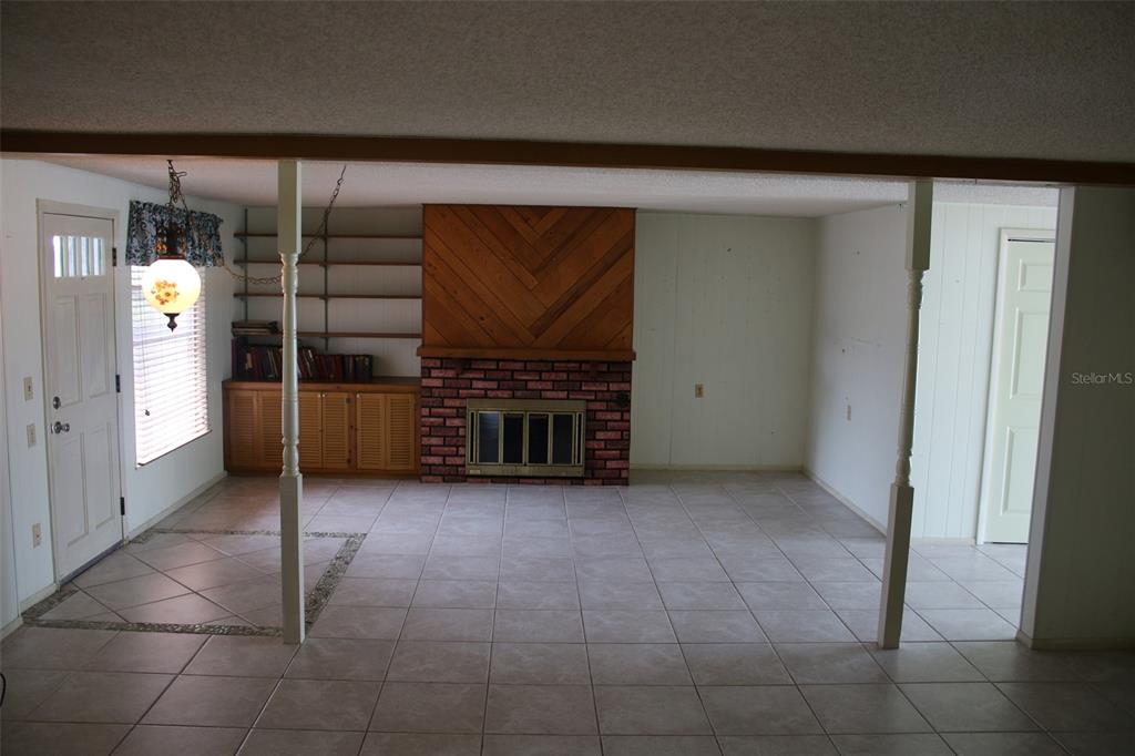 A living room features a brick fireplace, wood paneling, built-in shelving, and tile flooring — 407 N POMPANO AVENUE, SARASOTA, FL