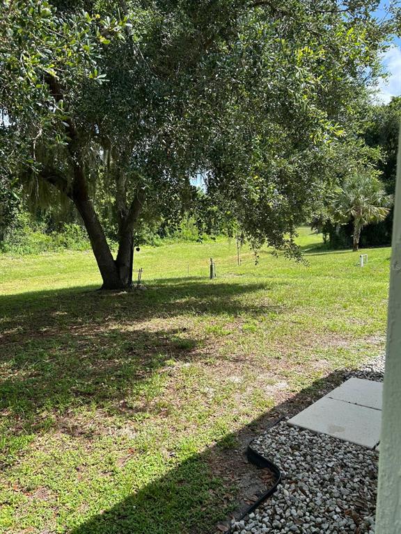 The exterior of a white, single-story house sits on a grassy, partially shaded lot — 3911 GEARY TERRACE, NORTH PORT, FL