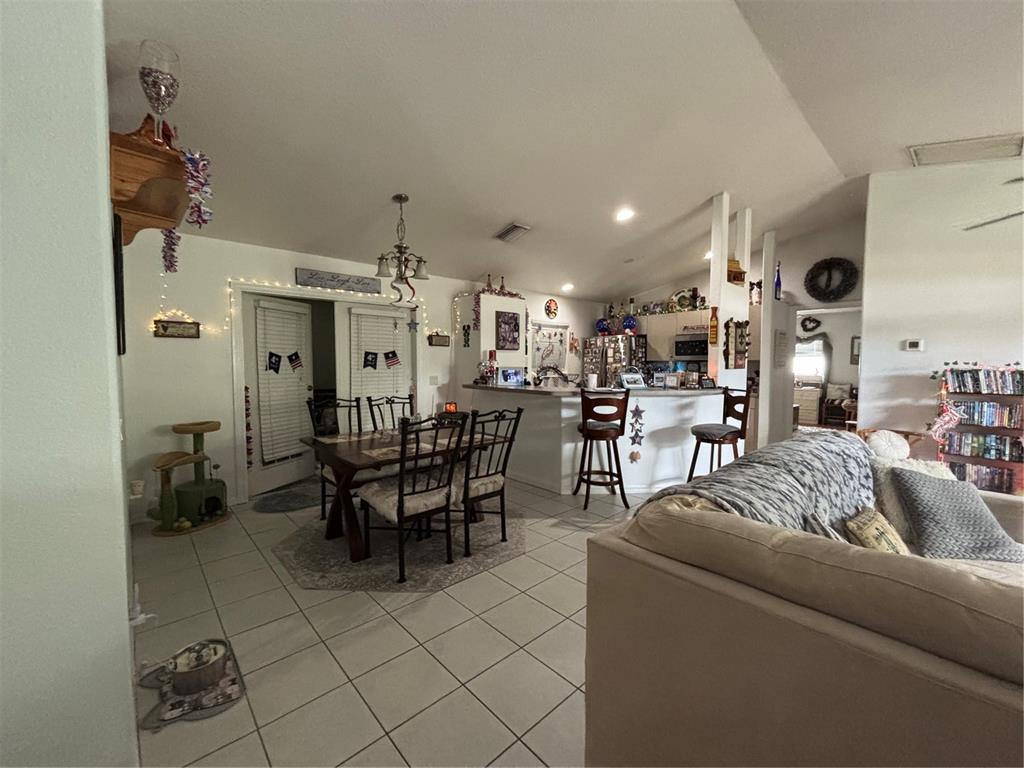 A large tree shades a grassy backyard with a gravel border and a concrete path — 3911 GEARY TERRACE, NORTH PORT, FL