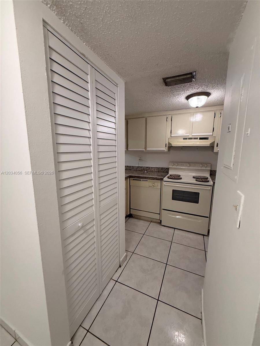 A galley-style kitchen features white appliances, light-colored cabinetry, and tiled flooring — 9917 W Okeechobee Rd # 510, Hialeah Gardens FL 33016, HIALEAH GARDENS, FL