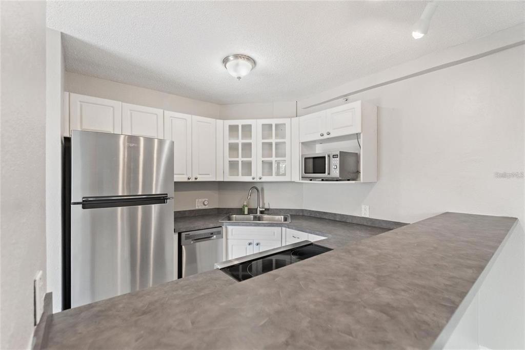 A kitchen features white cabinets, stainless steel appliances, and a dark gray countertop breakfast bar — 3315 58TH AVENUE S UNIT 314, ST PETERSBURG, FL