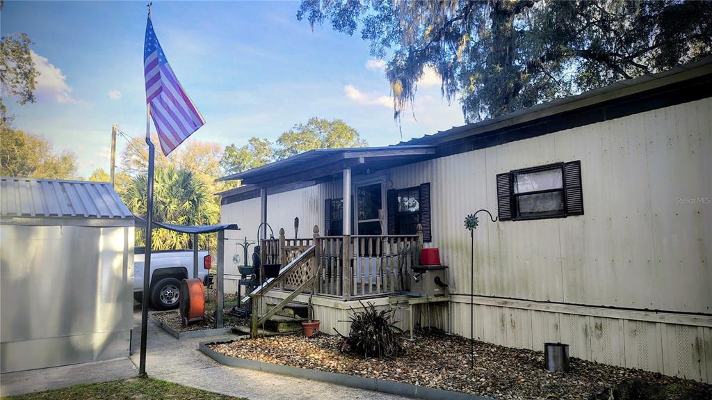 A mobile home with a front porch, an American flag, and a metal shed — 5990 NE 37TH STREET, SILVER SPRINGS, FL