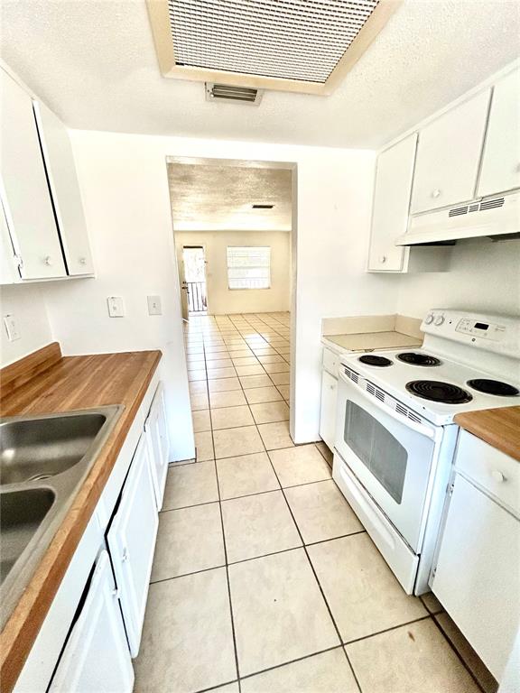 A kitchen features white cabinets, a wood countertop, a double sink, and a white stove — 1217 KENNEDY ROAD UNIT 06, DAYTONA BEACH, FL