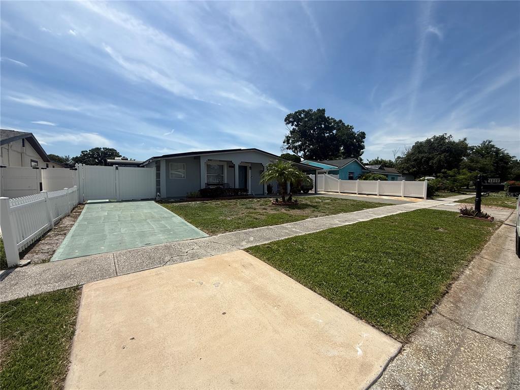 A single-story house with a green driveway, white fencing, and a front lawn — 4808 SIERRA MADRE DRIVE, TAMPA, FL