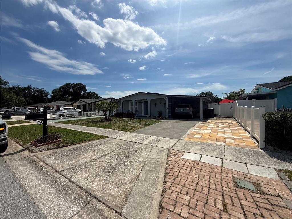 A single-story house with a carport, a paved driveway, and a white picket fence — 4808 SIERRA MADRE DRIVE, TAMPA, FL