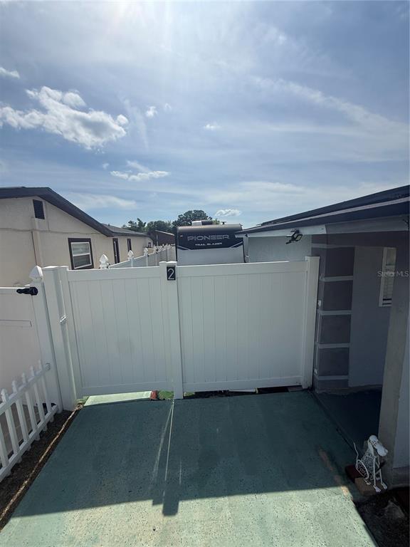 A white vinyl gate stands between two houses, with a travel trailer parked behind it — 4808 SIERRA MADRE DRIVE, TAMPA, FL