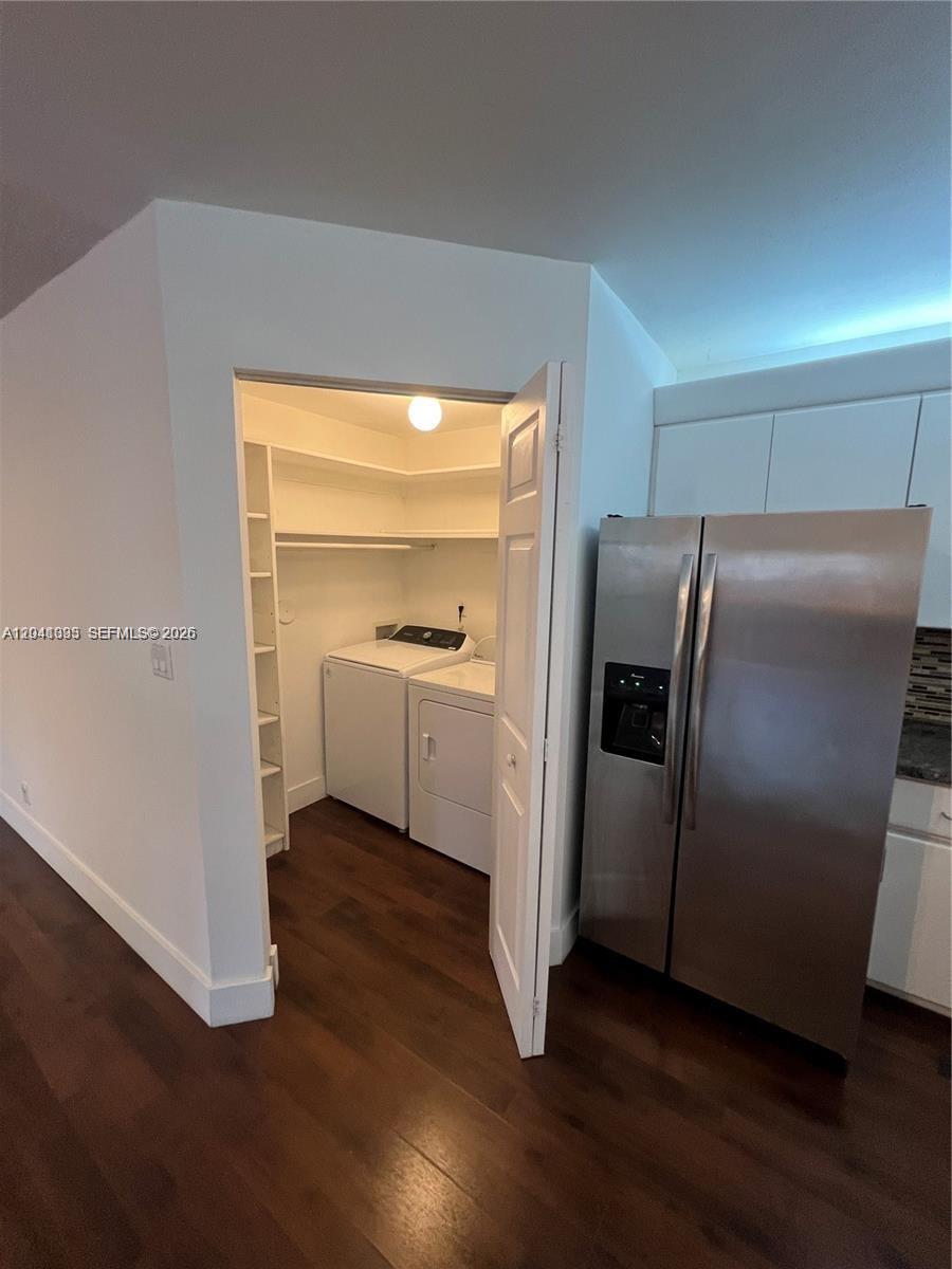 A laundry closet with white appliances and shelving is located next to a stainless refrigerator — 561 Racquet Club Rd # 21, Weston FL 33326, WESTON, FL