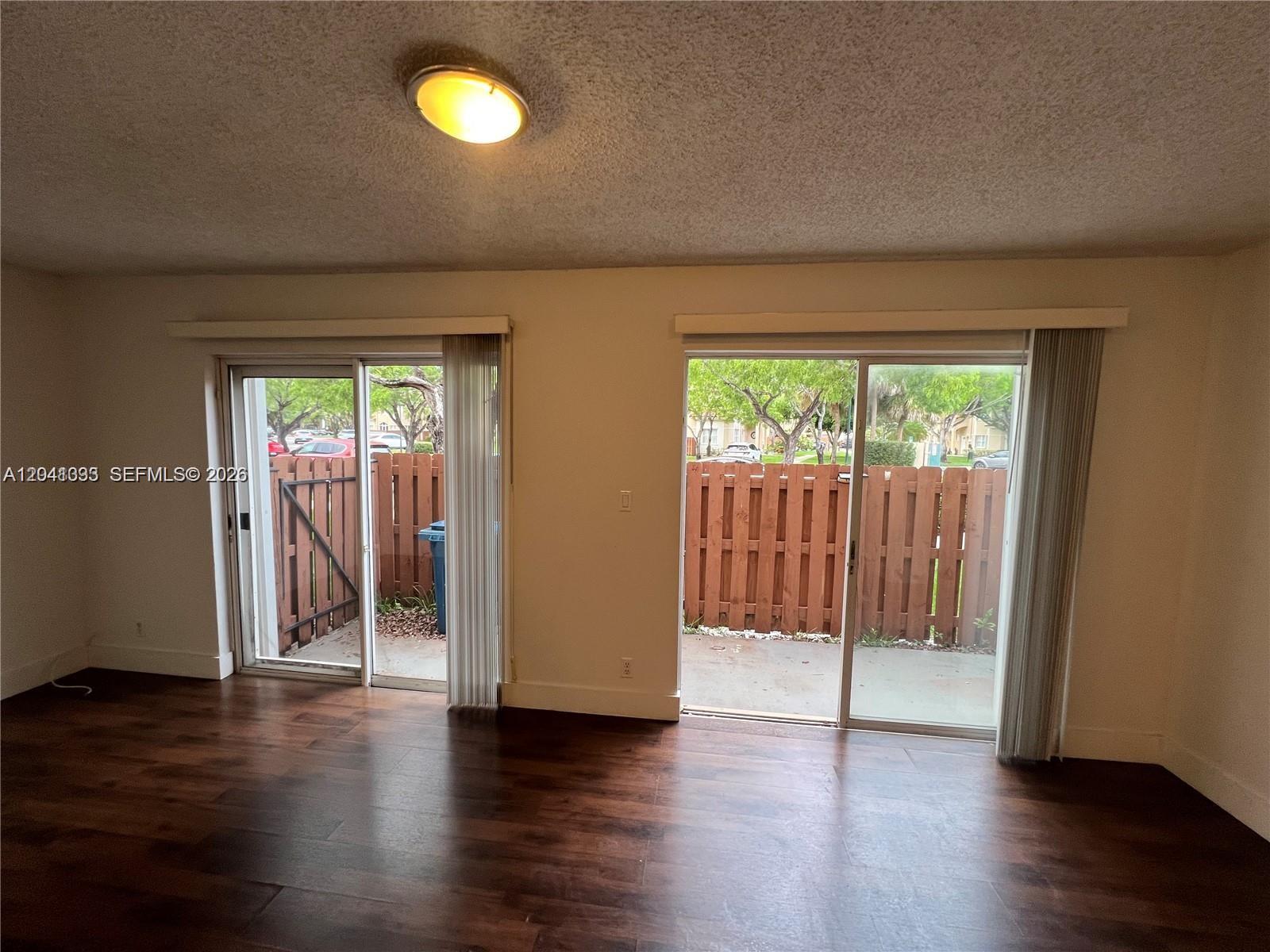 A room with dark wood-look flooring, a ceiling light, and two sliding glass doors — 561 Racquet Club Rd # 21, Weston FL 33326, WESTON, FL