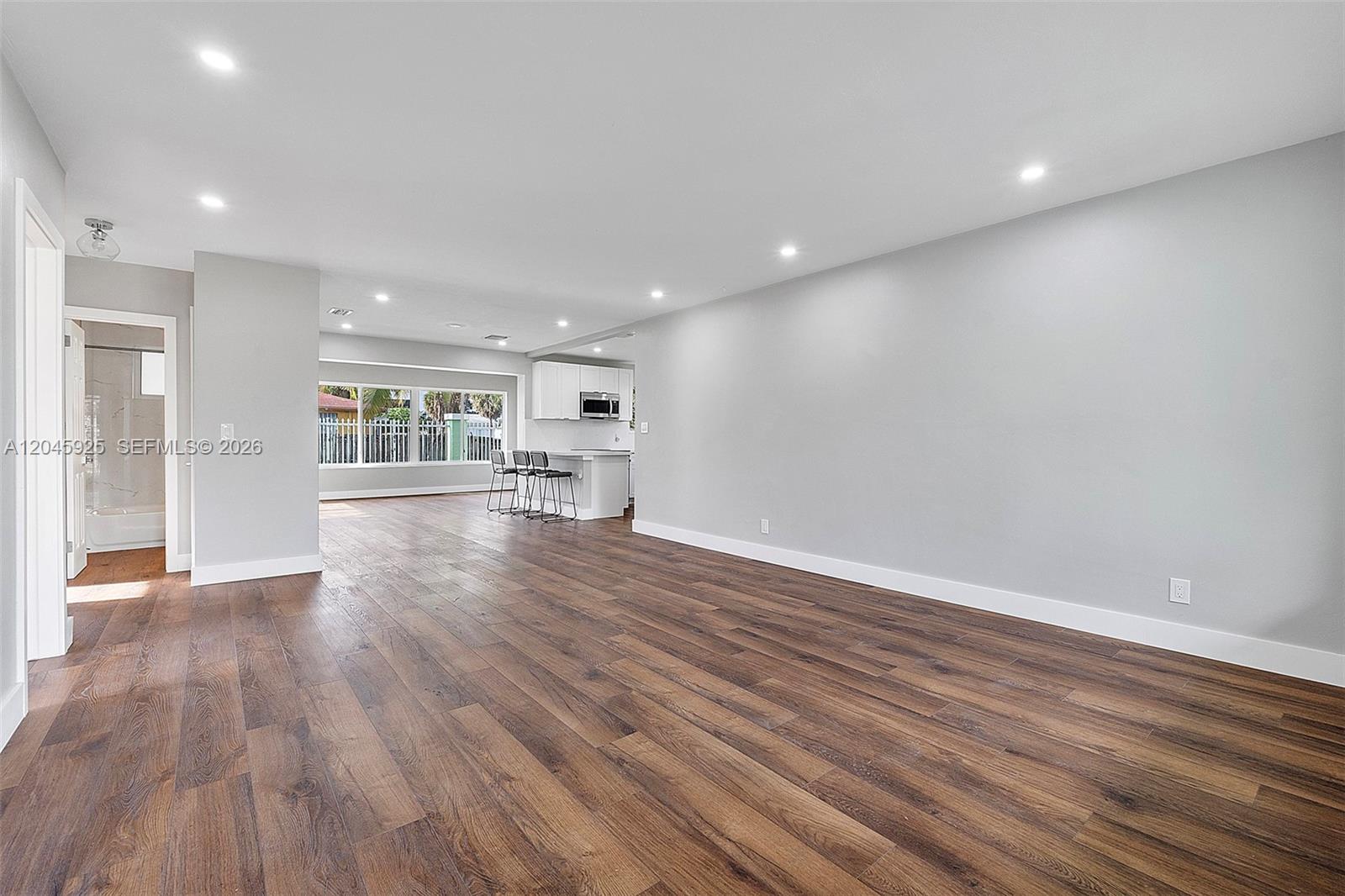 An open-concept living area features light gray walls, dark wood-look flooring, and a kitchen island — 2230 Atlanta St, Hollywood FL 33020, HOLLYWOOD, FL