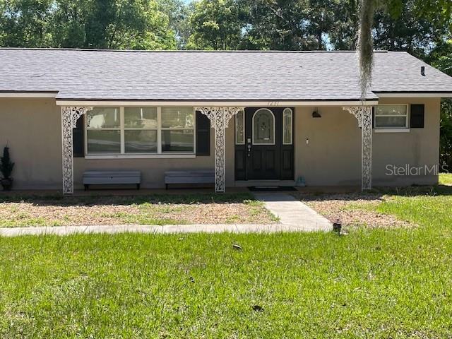 A single-story house with a gray roof, tan exterior, and decorative white porch supports — 1231 SE 40TH COURT, OCALA, FL