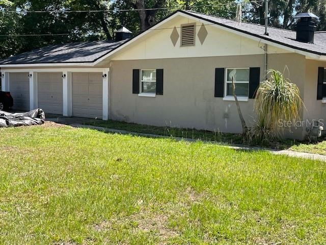 A tan house with a three-car garage and a dark shingled roof — 1231 SE 40TH COURT, OCALA, FL