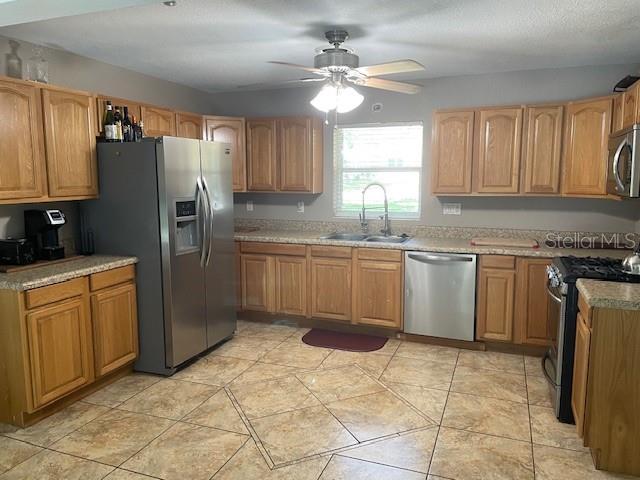 A kitchen features light wood cabinets, stainless steel appliances, and tan tile flooring — 1231 SE 40TH COURT, OCALA, FL