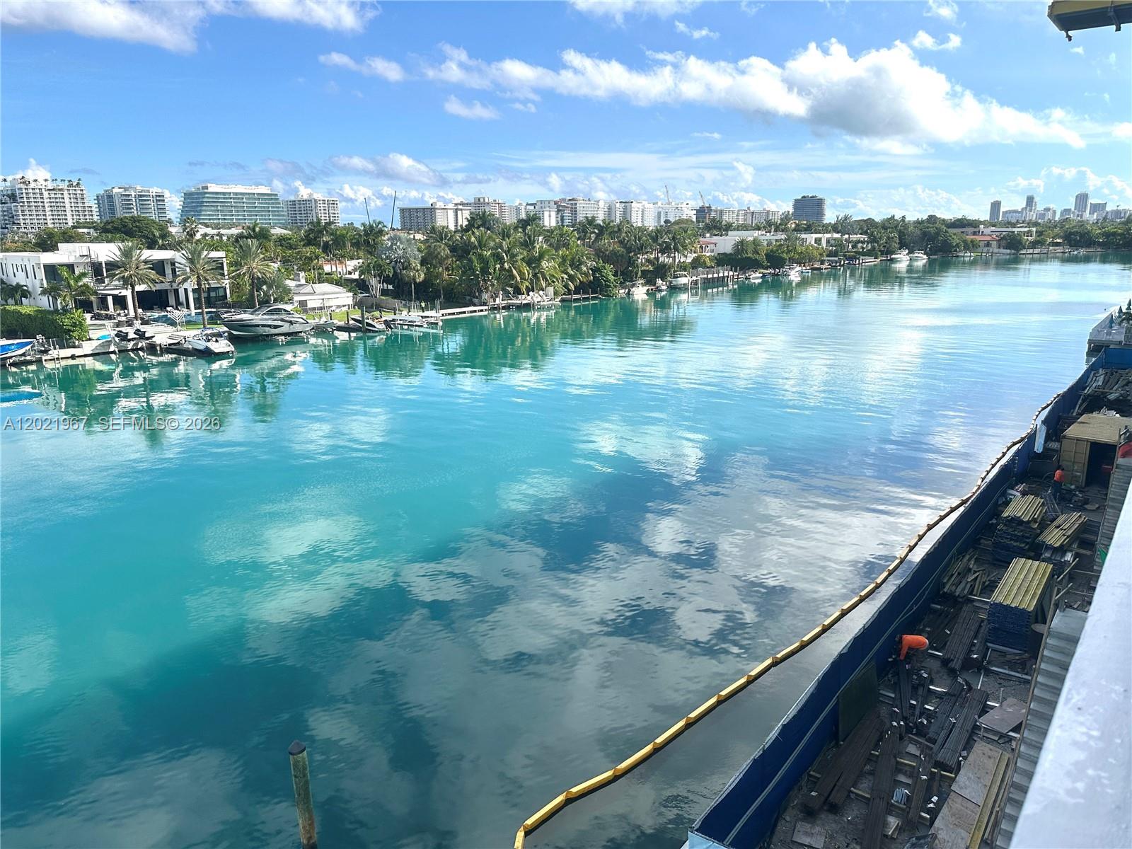 An elevated view shows a turquoise waterway with boats, palm trees, and distant city buildings — 9501 E Bay Harbor Dr # 5B, Bay Harbor Islands FL 33154, BAY HARBOR ISLANDS, FL