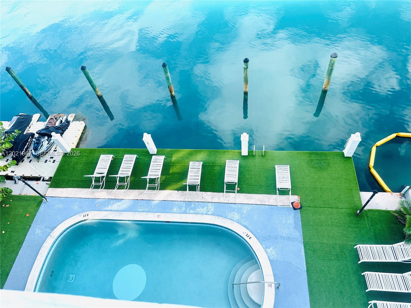 An aerial view shows a swimming pool and lounge chairs on a deck by water — 9501 E Bay Harbor Dr # 5B, Bay Harbor Islands FL 33154, BAY HARBOR ISLANDS, FL