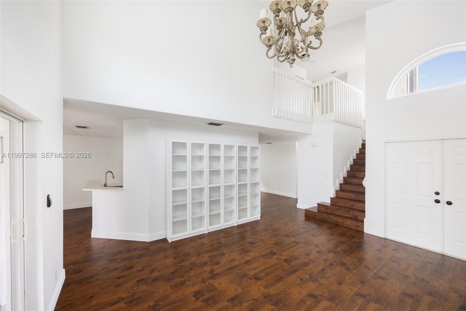 A bright, open-concept living area features dark wood flooring, a staircase, and built-in shelving — 8317 Bermuda Sound Way, Boynton Beach FL 33436, BOYNTON BEACH, FL