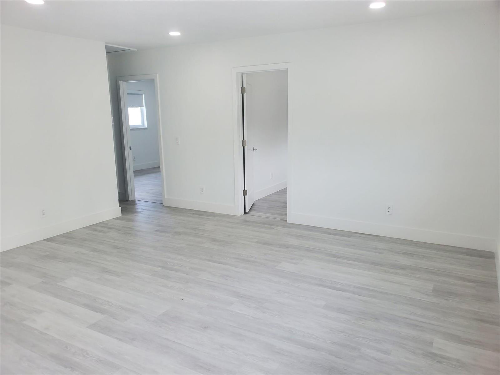 A bright, empty room features white walls, recessed lighting, and light gray wood-look flooring — 70 NW 13th Avenue # 2, Dania Beach FL 33004, DANIA BEACH, FL